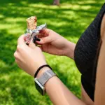Pessoa ao ar livre segurando uma barrinha energética durante atividade física, opção prática de alimentação esportiva