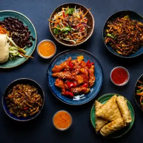 Pratos de comida asiática em bowls, com legumes e molhos variados, pães recheados e macarrão; referência à Segurança dos alimentos é prioridade dos chineses em um cenário culinário.