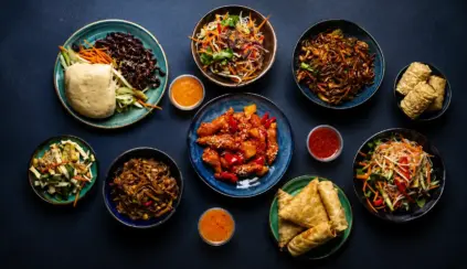 Pratos de comida asiática em bowls, com legumes e molhos variados, pães recheados e macarrão; referência à Segurança dos alimentos é prioridade dos chineses em um cenário culinário.