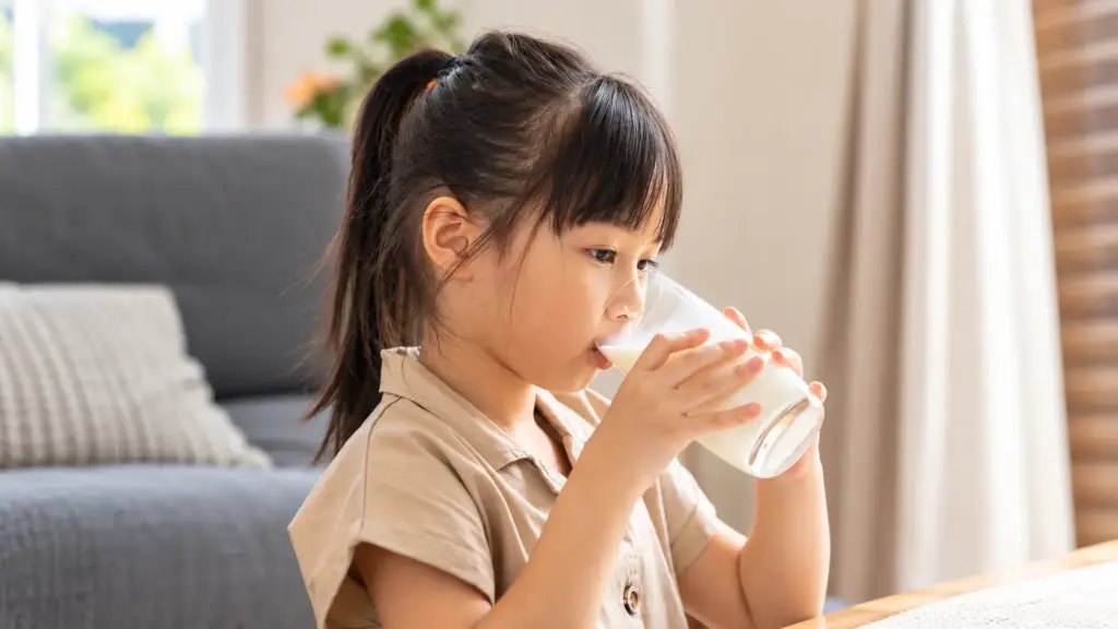 Criança bebendo leite em casa, lembrando o escândalo da melamina e a importância da segurança dos alimentos. Prioridade dos chineses na fiscalização e no consumo seguro.