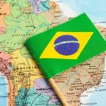 Bandeira do Brasil sobre mapa da América do Sul, com estados e países ao fundo; referência para tema de CBAM e carne brasileira.
