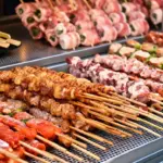 Churrasco na China com espetinhos grelhados em uma chapa industrial, com legumes e ervas na composição dos pratos.